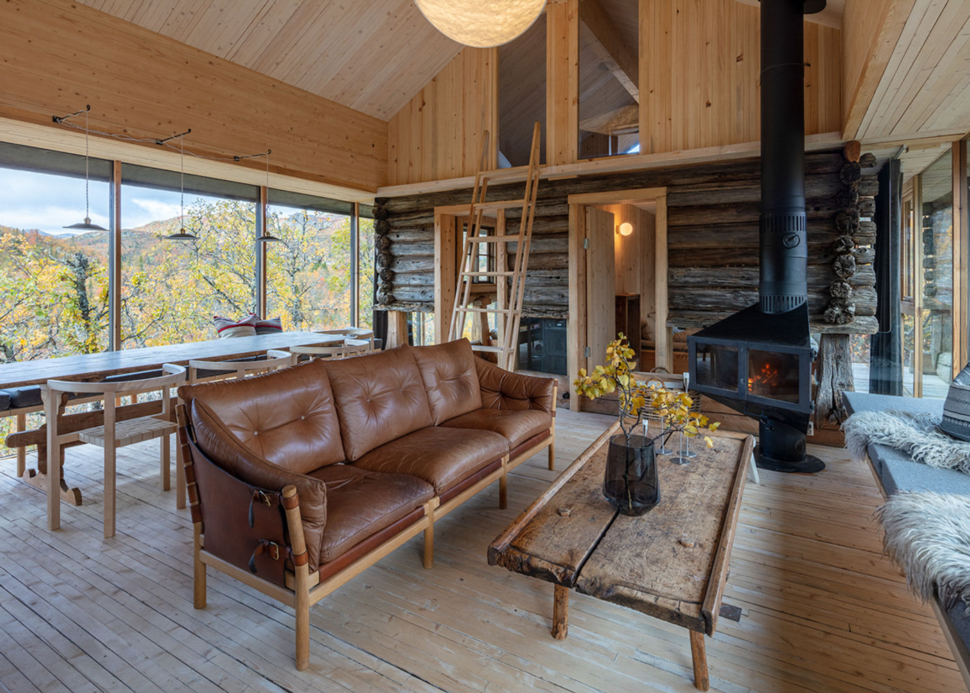 Living area with preserved log wall and triple-glazed façade to the birch forest